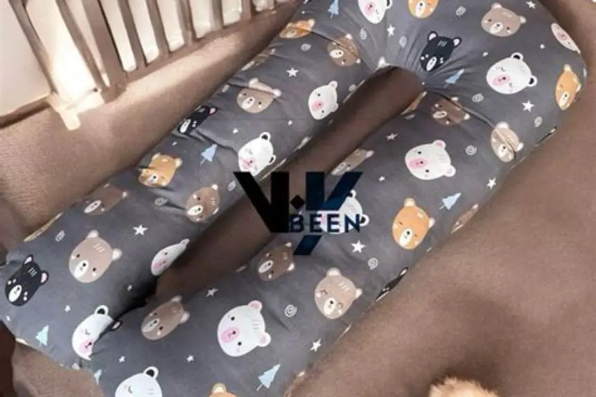 Parent nursing baby on couch with C-shaped pregnancy pillow supporting arm